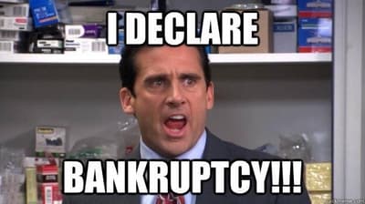 Screenshot from The Office TV series: A dark-haired man in a business suit with his mouth open and an uncomfortable look on his face. Michael Scott from the office yelling, 'I declare bankruptcy.'